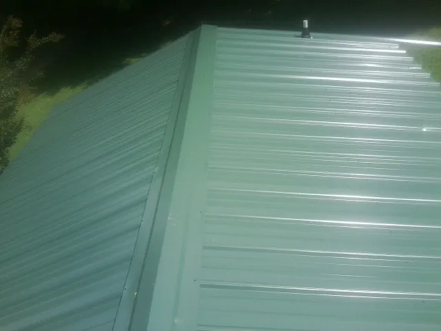 New green metal panels meeting at the ridge of a roof — Flat Roof Repair work by our crew in Rex