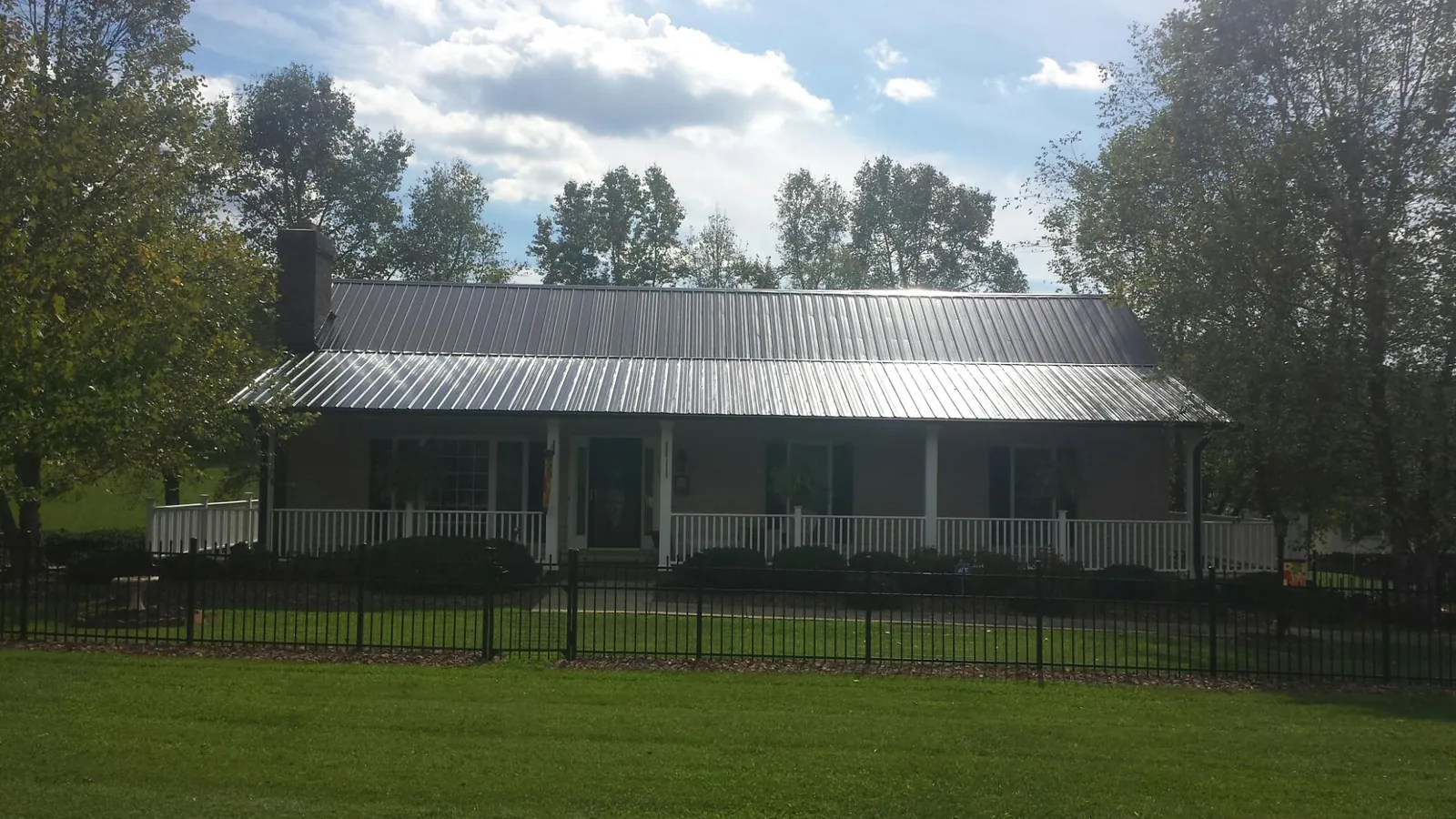 Gray metal roof on a brick ranch with a full width front porch — Gutter Guard Installation work by our crew in Rex